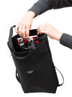Hands putting a book inside Braasis black Canvas Bag