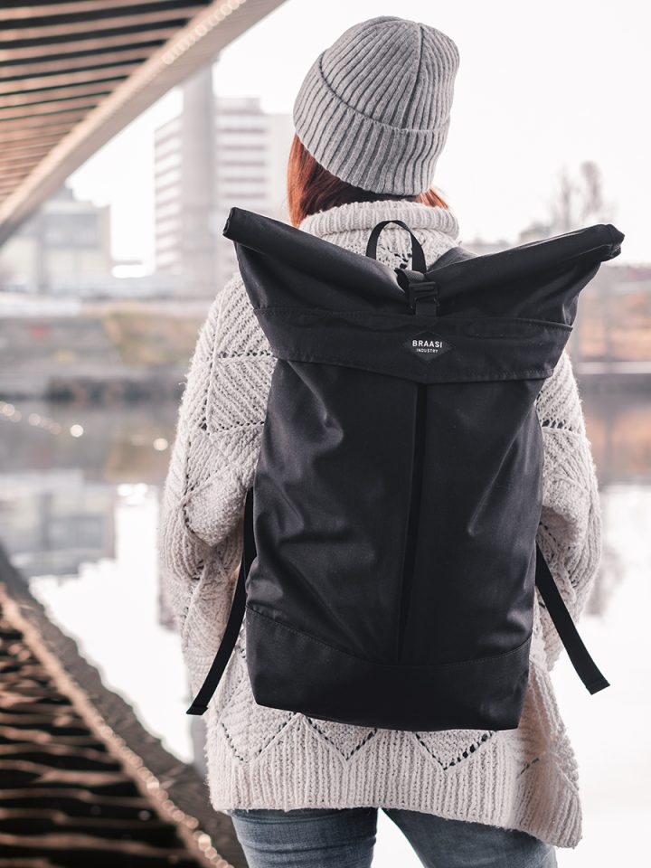A woman wearing the Braasi Levo urban backpack and the Merino Beanie in gray, made from 100% Merino wool.