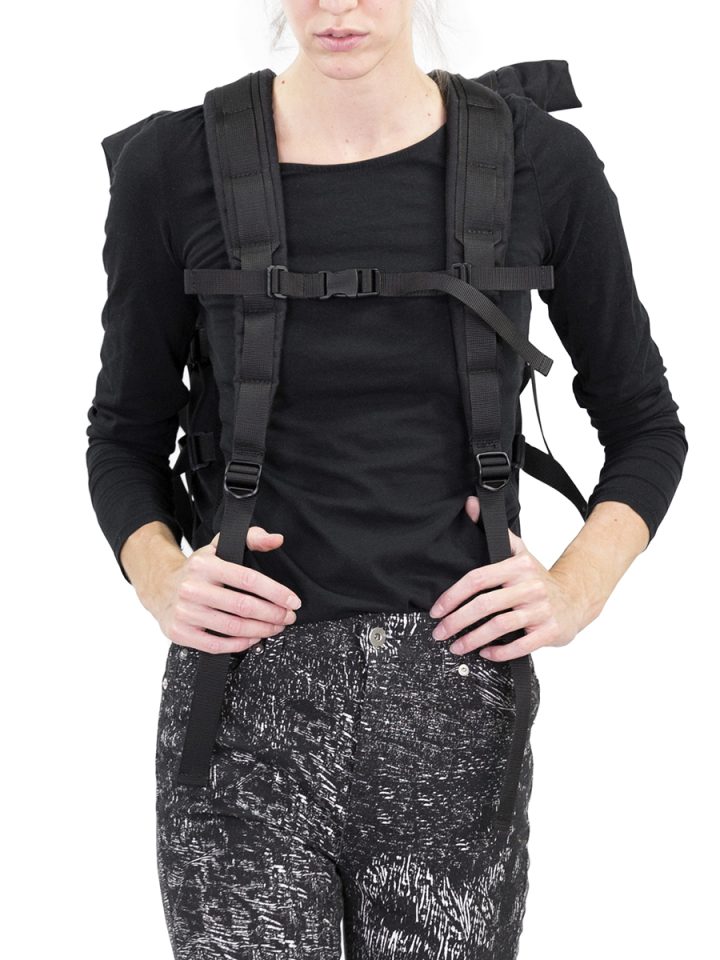 Woman wearing a black Braasi Wicker backpack with a chest strap.