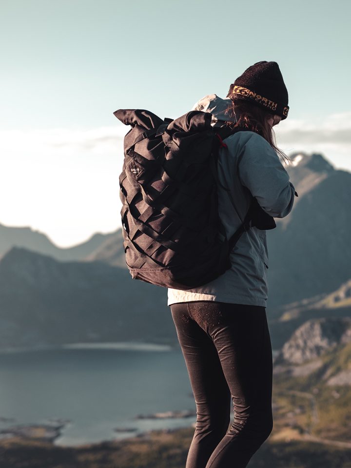 Overlooking a mountain range, a woman is wearing the Braasi Wicker black - a durable and waterproof backpack.