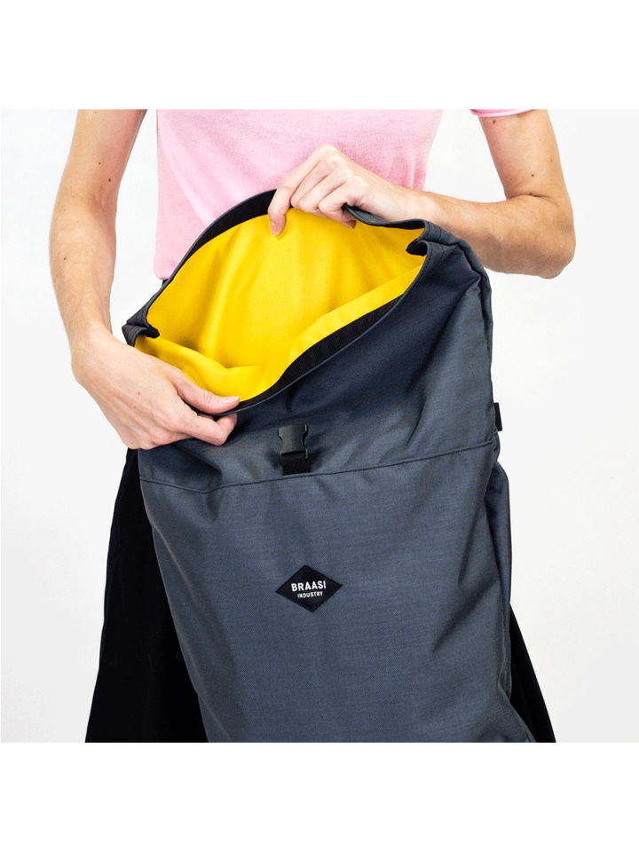 A model showing the yellow inner lining of the gray Basic Rolltop backpack from Braaso